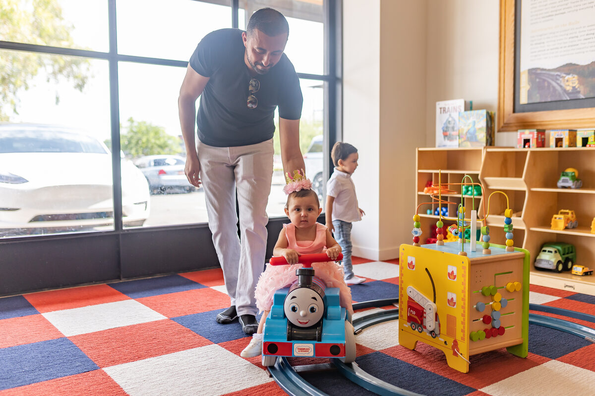 Dad pushing his daughter on the Thomas train ride in the play area
